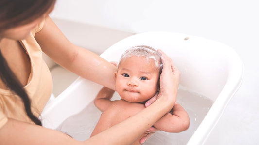 Baby being given a bath in a little white tub