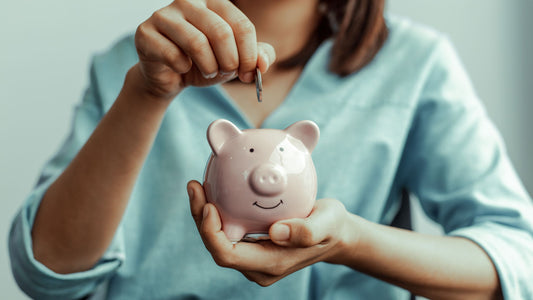 A person dropping coins into a piggy bank